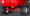 Underside of a red agricultural vehicle showing large off-road tires and red axle with yellow cap.
