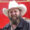 Man with a full beard wearing a white cowboy hat and dark jacket, smiling outdoors