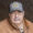 Portrait of an older man wearing a brown jacket and a blue cap with a Springfield Livestock Marketing Center logo.