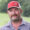 Man wearing a red cap with 'Martin's Farms' logo, plaid shirt, outdoors with greenery in the background.